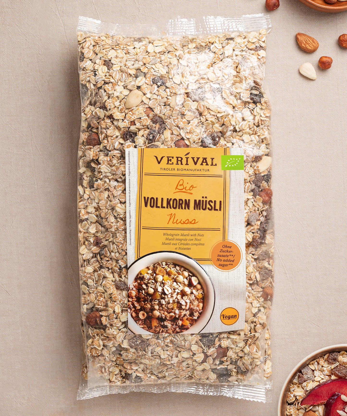 Eine Grpßpackung Nuss-Vollkorn-Müsli von Verival Bio liegt auf einer hellen Unterlage, umgeben von verstreuten Nüssen und Haferflocken und bietet ein leckeres, ballaststoffreiches, veganes Frühstück für deinen Tag.