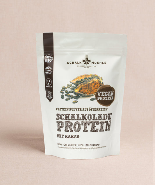 Der Schoko-Protein-Mix „Schalkolade“ von Schalk Mühle überzeugt durch seinen intensiven Kakaogeschmack. Das Etikett „Schalkolade Protein mit Kakao“ zeigt Kakaobohnen und -samen und liefert 100 % Bio-Qualität und -Geschmack. Ideal für Shakes, Müsli und Milchkakao mit hohem Proteingehalt aus hochwertigen Quellen.