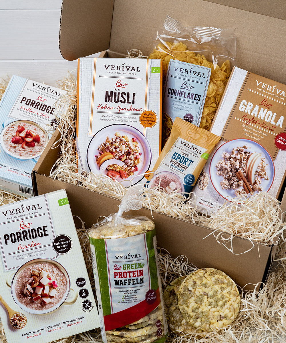 Das Set „Gotta Be Glutenfree“ von Verival Bio beinhaltet glutenfreie Frühstücksartikel wie Porridge, Müsli, Granola, Cornflakes sowie Proteinwaffeln . Diese sind elegant auf Holzwolle angerichtet und ergeben ein perfektes Bio-Frühstücksset.