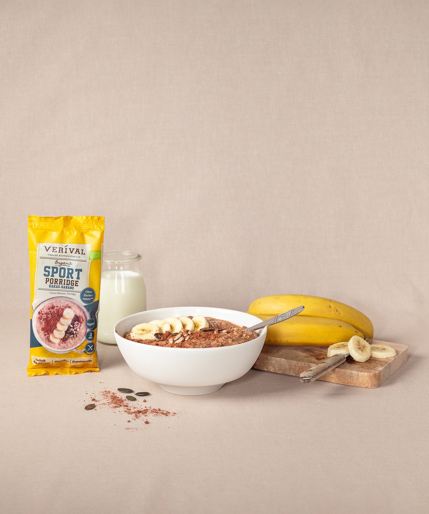 Das Verival „Breakfast Lover“-Set besteht aus Protein Frühstück Sport Porridge und einer eleganten Porzellan-Schüssel. Daneben ist  ein Glas Milch und ein Schneidebrett mit Bananen zu sehen.